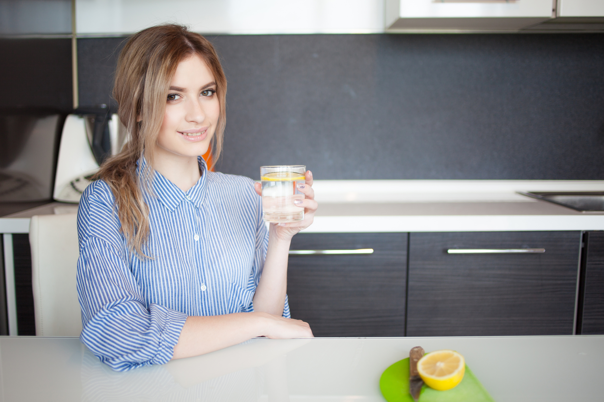 Beautiful girl starts his morning with glass of water with lemon
