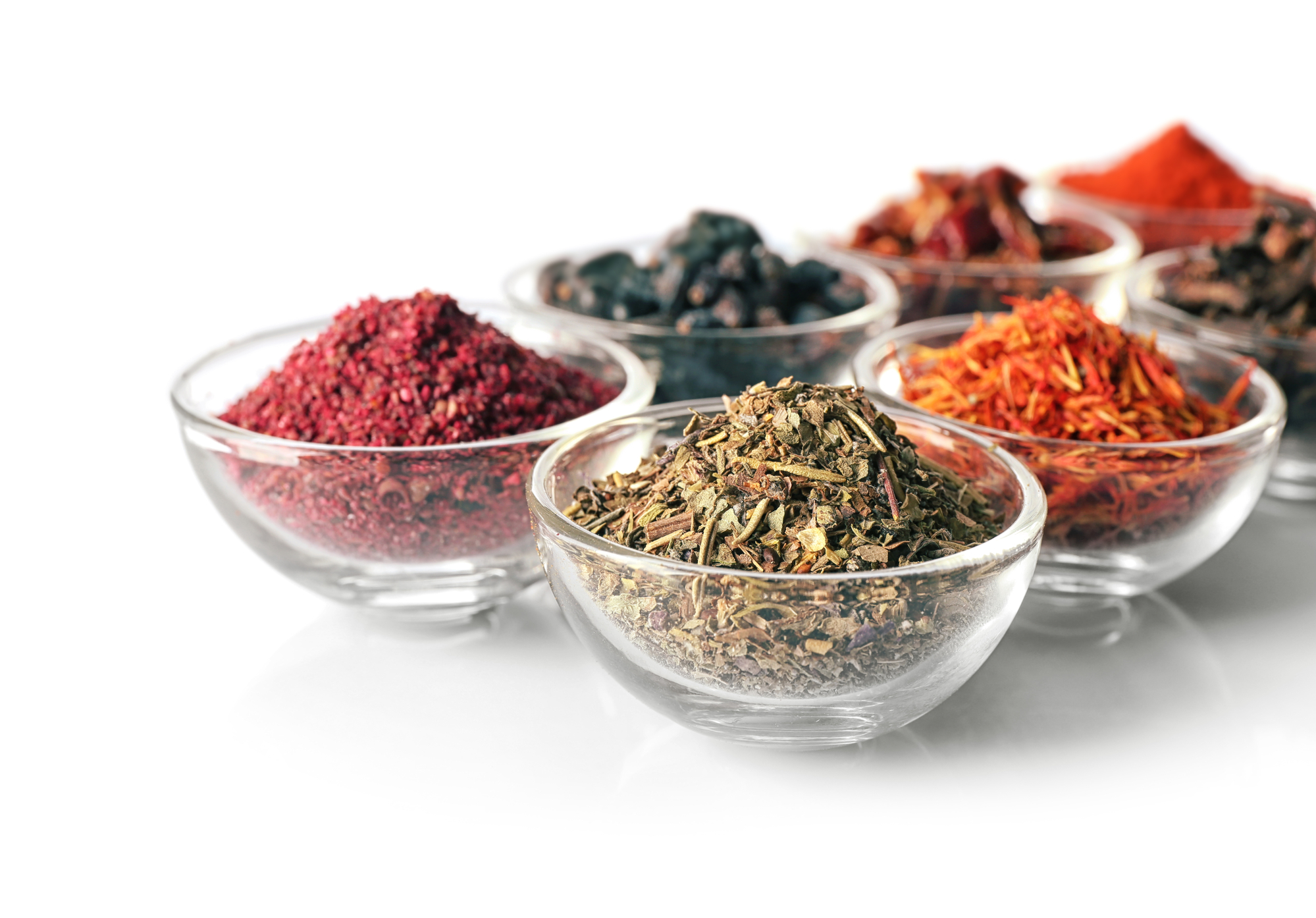 Assortment of spices in glass bowls on white background