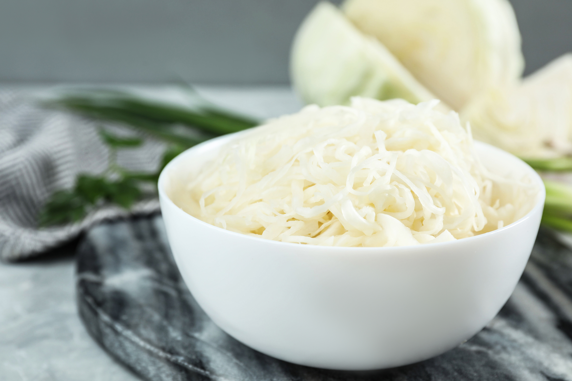 Tasty fermented cabbage on light grey table, closeup