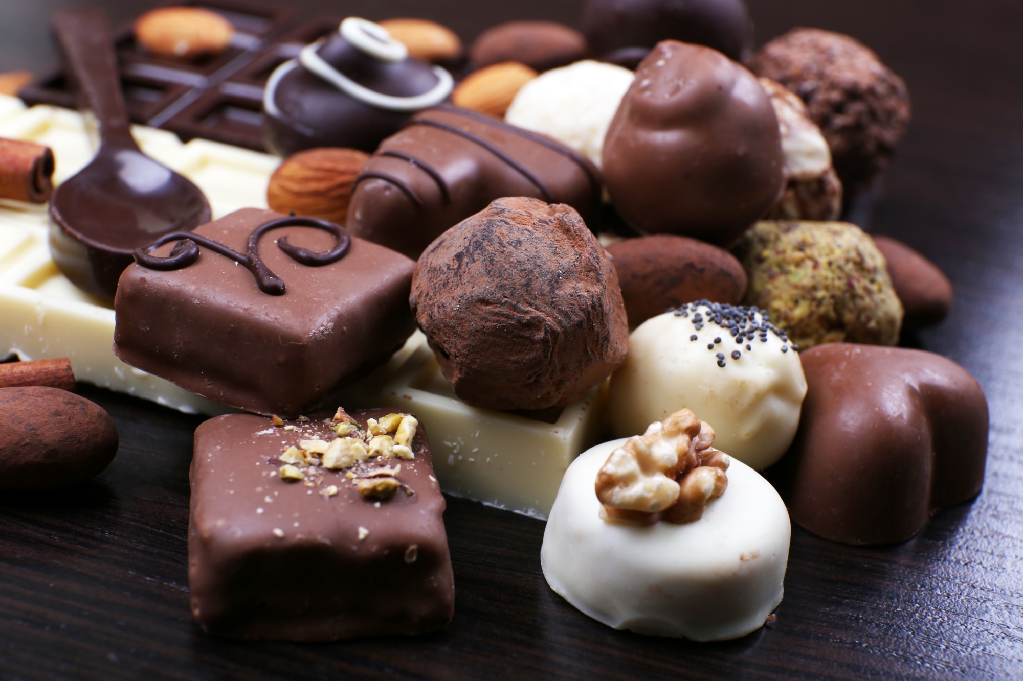 Group of sweet chocolate truffles on the dark wooden smooth background