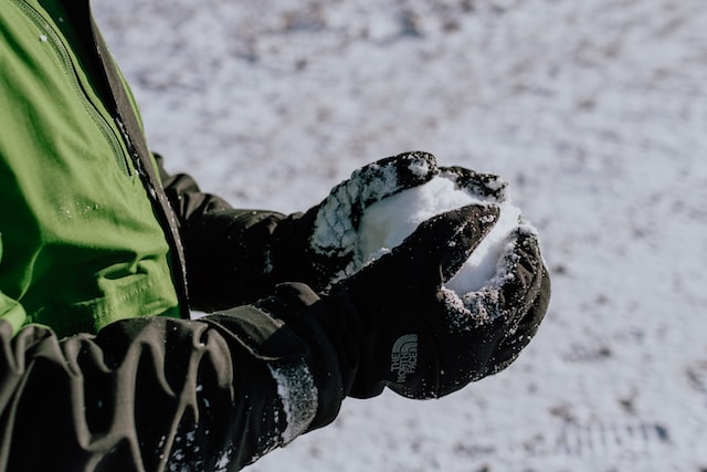 a person in quilted gloves holds snow