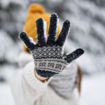 person in white and black knit gloves