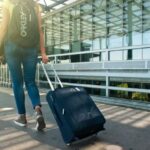 Traveling - Woman Walking on Pathway While Strolling Luggage