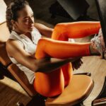 Diets - Woman in White Tank Top and Orange Pants Sitting on Black and Brown Chair