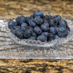 Superfoods - a glass bowl filled with blueberries on top of a counter