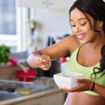 Healthy Eating - Woman Eating Strawberry in the Kitchen