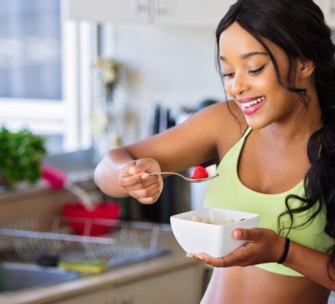 Healthy Eating - Woman Eating Strawberry in the Kitchen