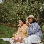 Eating - Ethnic mother and daughter eating apples during picnic