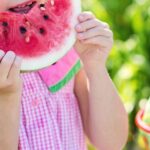 Healthy Eating - Girl Eating Sliced Watermelon Fruit Beside Table