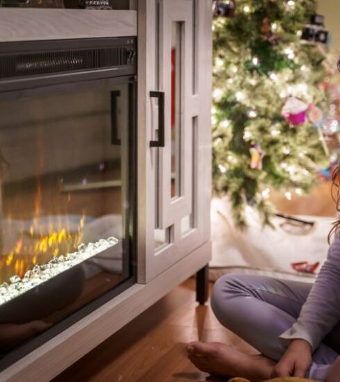 Holidays - woman in gray long sleeve shirt sitting on floor beside fireplace