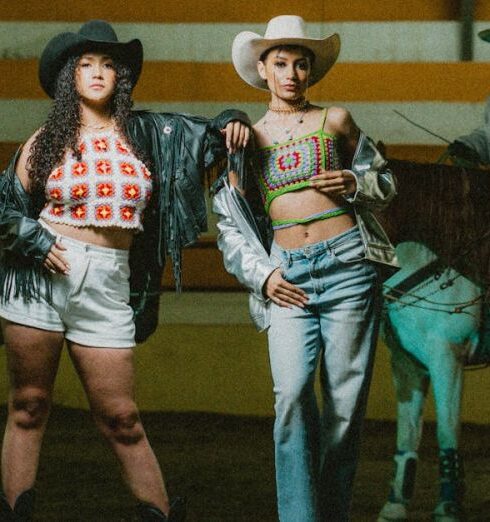 Tops - Two women in cowboy hats standing next to horses