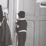 Coats - A child standing in front of a door