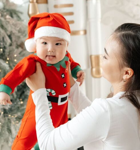 Rompers - A woman holding a baby in front of a christmas tree