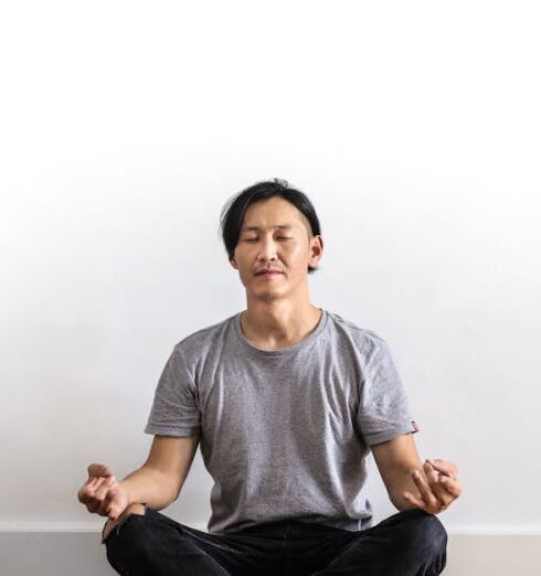 Mindfulness - Photo of Man in Gray T-shirt and Black Jeans on Sitting on Wooden Floor Meditating