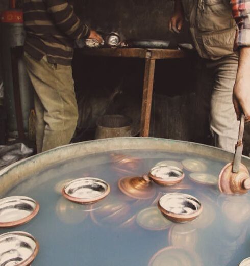 Techniques - Two Men Taking Dishes out of a Barrel Filled with Water