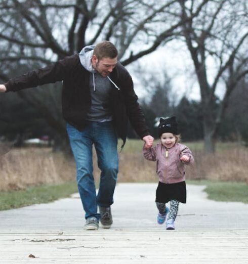 Parenting - A Father and his Little Girl Running on a Park Pathway