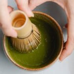 Detoxing - Top view of crop anonymous person using bamboo whisk while brewing hot matchaa tea ceremony