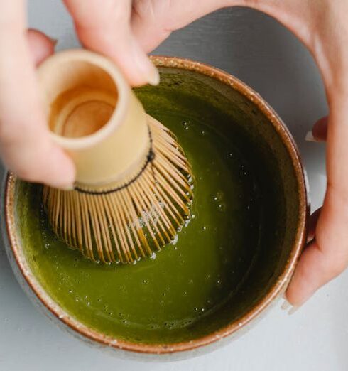 Detoxing - Top view of crop anonymous person using bamboo whisk while brewing hot matchaa tea ceremony