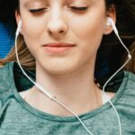 Mindfulness - Young woman listening to music in earphones in apartment