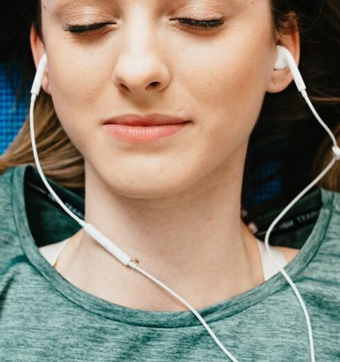 Mindfulness - Young woman listening to music in earphones in apartment