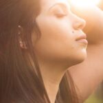 Breathing - Side View Photo of Woman With Her Eyes Closed Holding Her Her As Sunlight Shines on Her Face