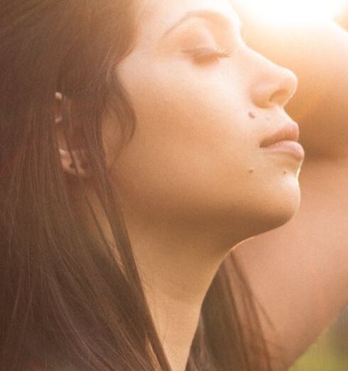 Breathing - Side View Photo of Woman With Her Eyes Closed Holding Her Her As Sunlight Shines on Her Face