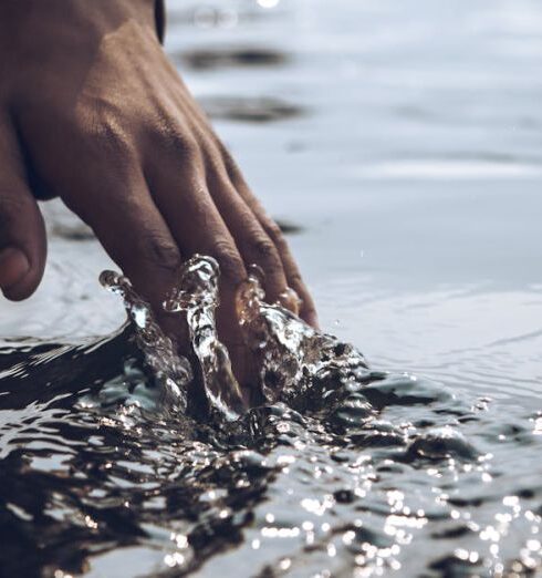 Touch - Close-Up Photo of a Person's Hand Touching Body of Water