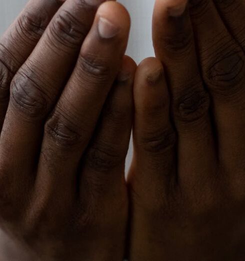 Mindfulness - Selective focus of crop anonymous African American man wearing white turtleneck praying with open hands