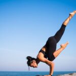 Balance - Low Angle View of Woman Relaxing on Beach Against Blue Sky