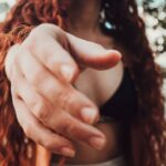 Approach - Photo of Woman Black Brassiere and White Miniskirt Leaning Forward While Posing With Her Hand Out