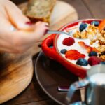 Eating - Person Holding Spoon and Round Red Ceramic Bowl With Pastries