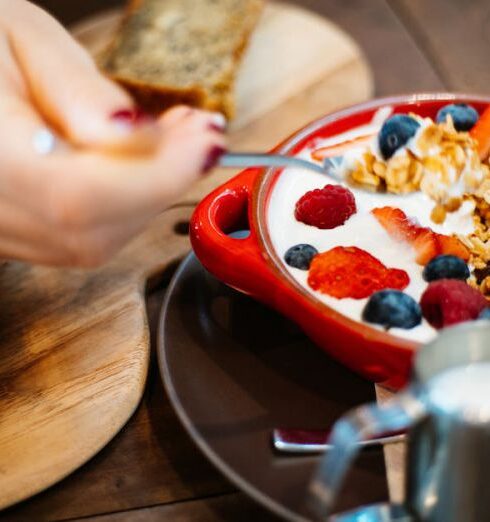 Eating - Person Holding Spoon and Round Red Ceramic Bowl With Pastries