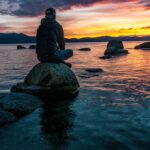 Reflection - Person Sitting on Rock on Body of Water