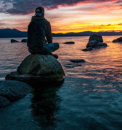 Reflection - Person Sitting on Rock on Body of Water