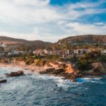 Adventures - Brown Mountains with Buildings Beside Blue Sea