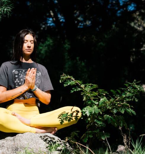 Mindfulness - Photo of Woman Doing Yoga While Sitting on Rock