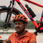 Routine - Photo of Man Wearing Orange Polo Shirt Sitting Beside His Bike