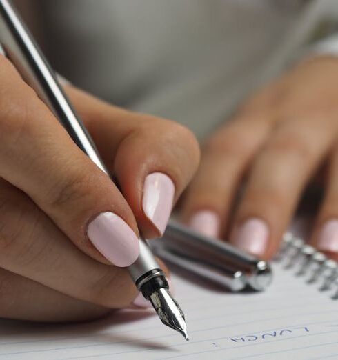 Schedule - Woman in White Long Sleeved Shirt Holding a Pen Writing on a Paper