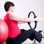 Pilates - Woman in Red Shirt Sitting on Fitness Equipment