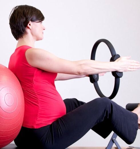 Pilates - Woman in Red Shirt Sitting on Fitness Equipment