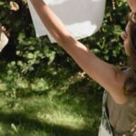 Routine - A Woman Hanging a White Cloth on a Clothes Line