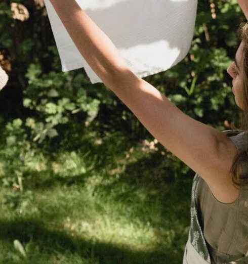 Routine - A Woman Hanging a White Cloth on a Clothes Line