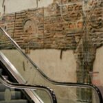 Routines - A woman is walking down an escalator in a subway station