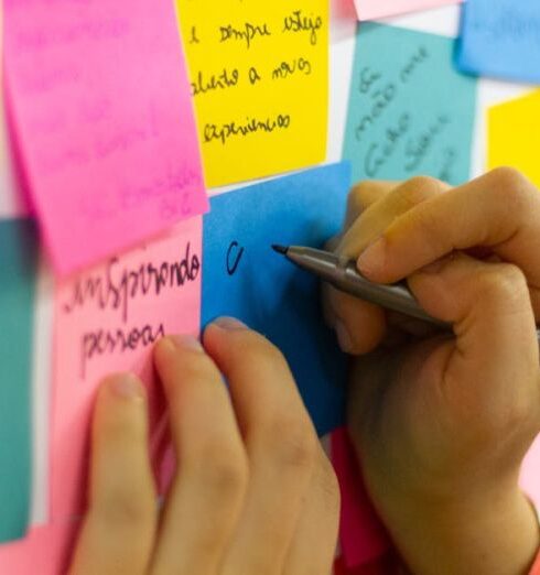 Improvement - Person Writing on Pink Sticky Notes