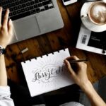 Lifestyle - Person Sitting Facing Laptop Computer With Sketch Pad