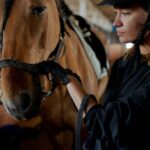 Pet - Pensive woman stroking horse in stable