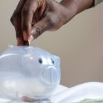 Savings - Person Putting Coin in a Piggy Bank