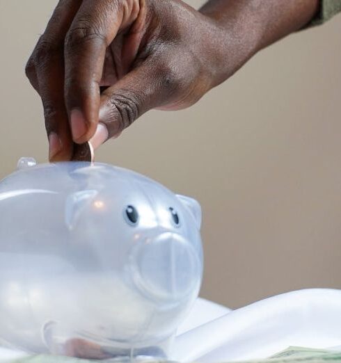 Savings - Person Putting Coin in a Piggy Bank