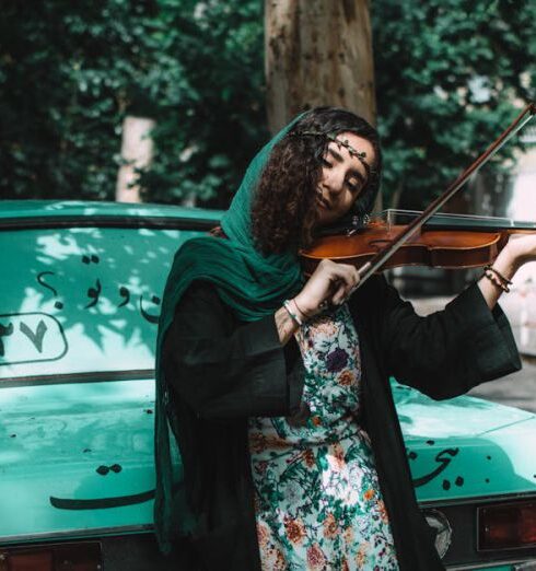 IRAs - Woman Playing Violin While Leaning On Green Vehicle