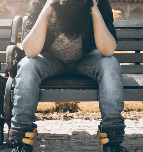 Stress - Man in Black Shirt and Gray Denim Pants Sitting on Gray Padded Bench